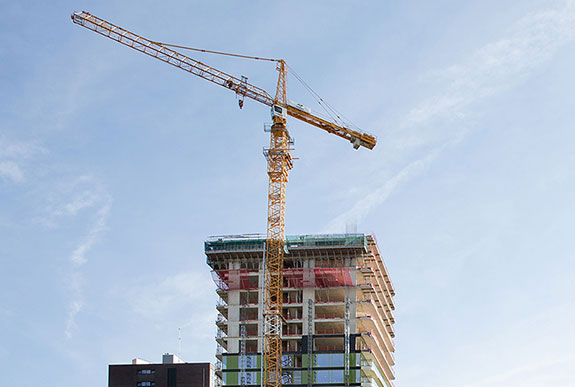 Afbeelding van het verbouwen van een groot gebouw met op de voorgrond een kraan.